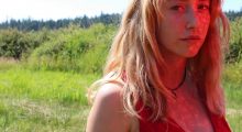 A blonde woman standing in a field from Avalon Fast's film "Honeycombing"
