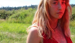 A blonde woman standing in a field from Avalon Fast's film "Honeycombing"