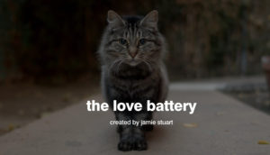 A grey-brown cat staring at the camera over a title card, "The Love Battery"