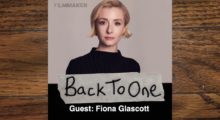 A young white woman -- actor Fiona Glascott -- in a black top against a neutral backdrop