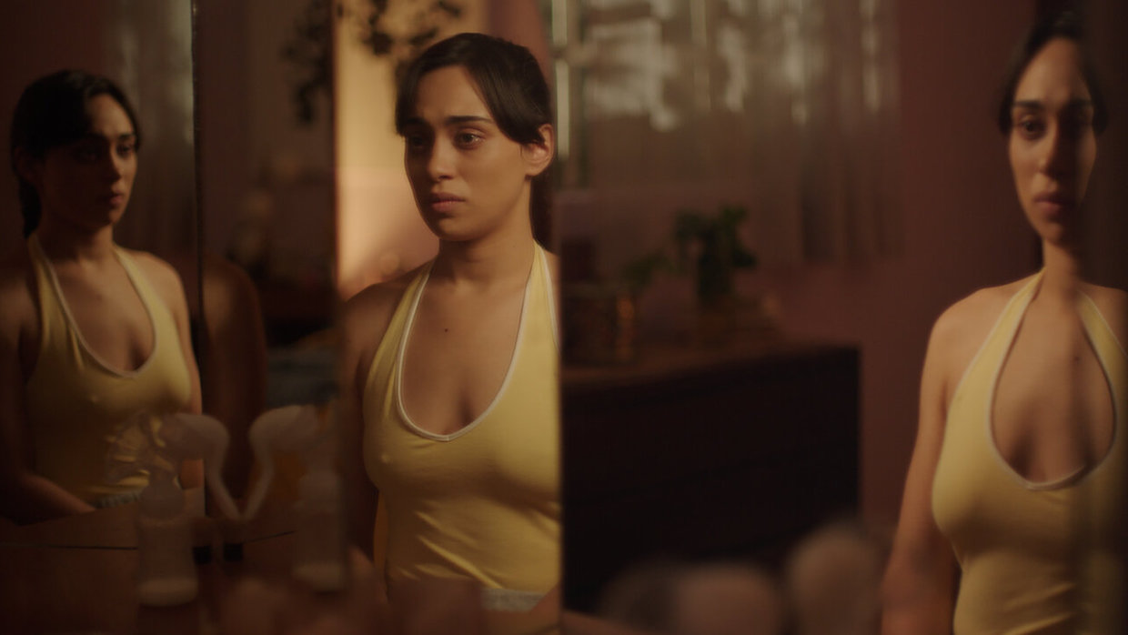 A woman stands in front of a triptych of mirrors, each slightly distorting her body's reflection.