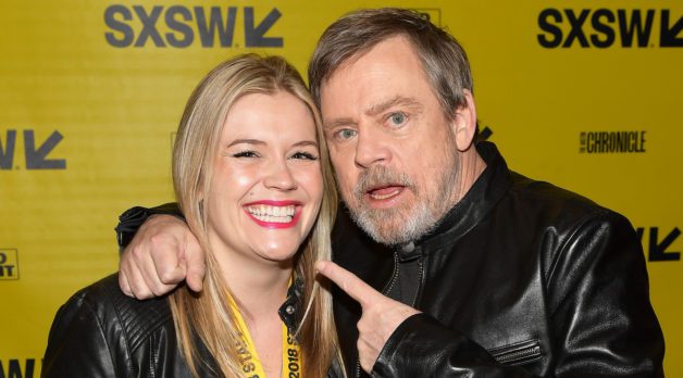 Claudette Godfrey, a young woman with straight, blond hair and red lipstick, poses with actor Mark Hamill, who has salt and pepper hair and a beard.