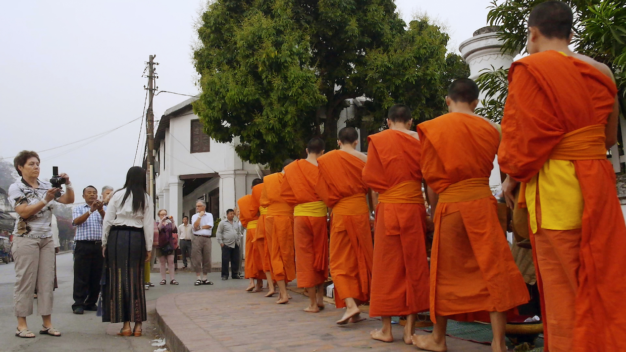 A tourist photographs monks in Laos in Kimi Takesue's Onlookers