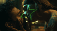 A woman holds a man's face in her hands as she leans in for a kiss. A green star in projected over her side profile.