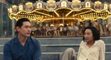 Two 30-something Koreans, a man and a woman, sit in front of a carousel.