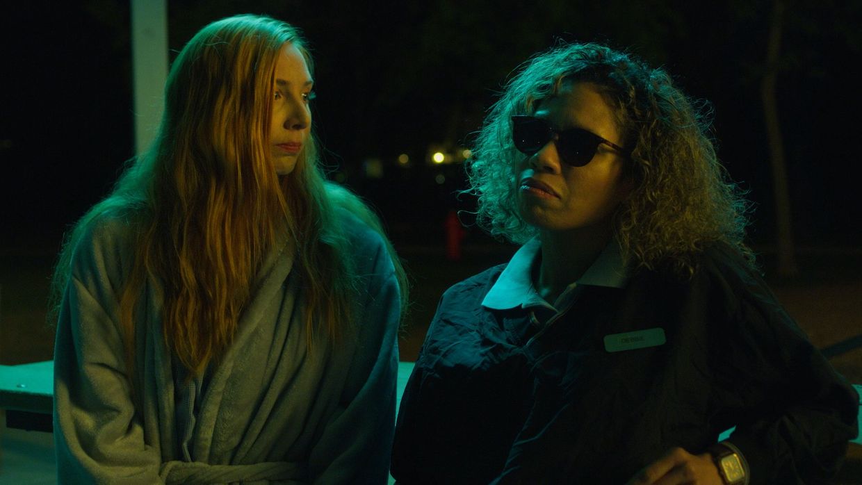A woman with long, straight blonde hair stands next to a woman with shoulder-length curly brown hair.