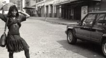 a Black trans woman sex worker poses in an '80s-era dress in an archival image from the 1980s of "The Stroll" in the Meatpacking District of Manhattan.