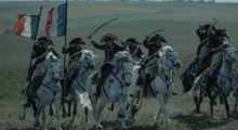 A French cavalry ride with swords drawn and two French flags waving in the wind as they charge.