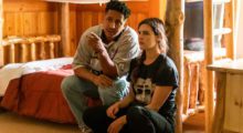 A man sits on a bed and directs a young actress.