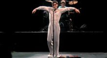 Talking Heads frontman David Byrne extends his arms and sings into the microphone circa 1983.