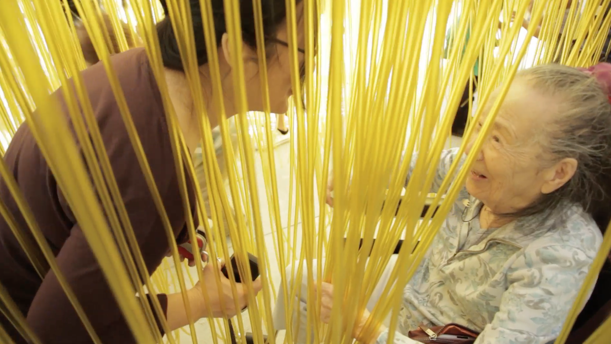 Filmmaker Rea Tajiri bends over her mother, who is sitting in a wheelchair.