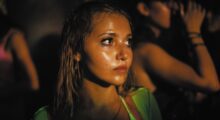 A young woman in a green top stands in a crowd.