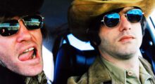 Two white men in sunglasses and large-brimmed hats are mugging for the camera.