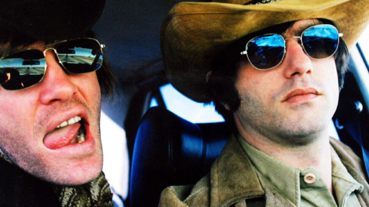 Two white men in sunglasses and large-brimmed hats are mugging for the camera.