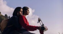 Two Malaysian girls ride a scooter during dusk.