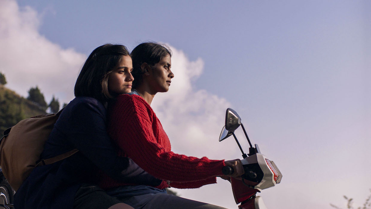 Two Malaysian girls ride a scooter during dusk.