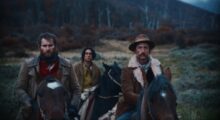 Two white men sit on horses in the foreground, while their Chilean guide sits behind them.