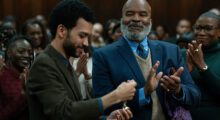 A Black man receives a medal while a crowd of onlookers cheers.