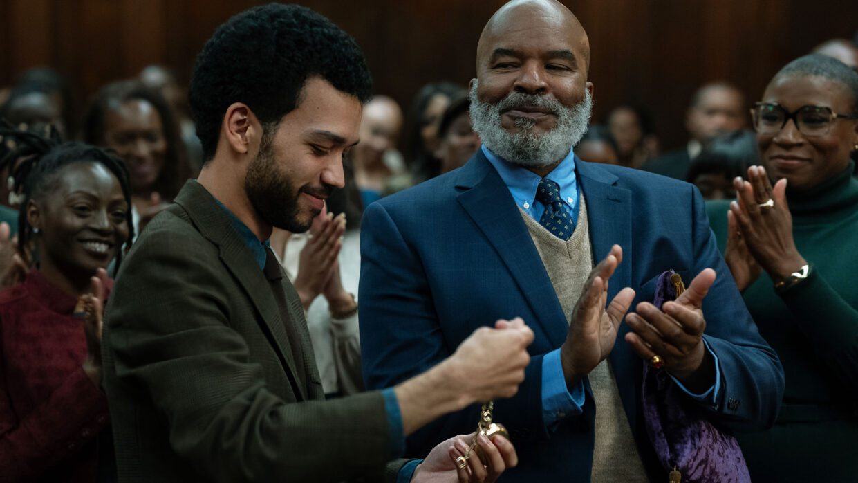 A Black man receives a medal while a crowd of onlookers cheers.