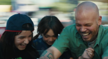 One man in a green shirt and his two daughters are laughing