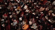 An overhead view of a seated audience in a large auditorium.