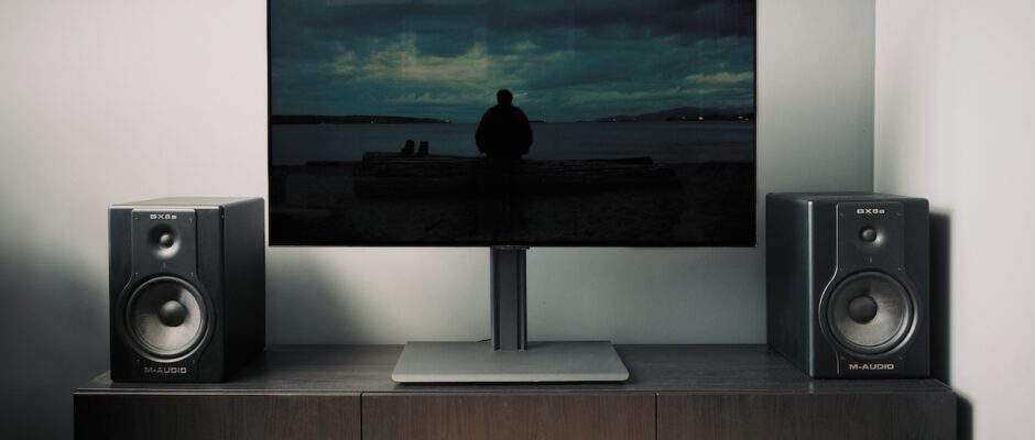 A television displaying na image during daytime with of a man on a dark beach in a living room.