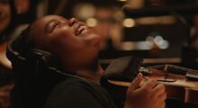 A young child smiles while playing the violin.