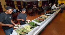 Men on a film set select their food options from a catered buffet on a film set.
