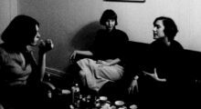 Three women sit in a living room having a discussion.