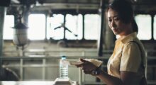 A Chinese woman holds a styrofoam container of rice while eating on a deserted boat deck.
