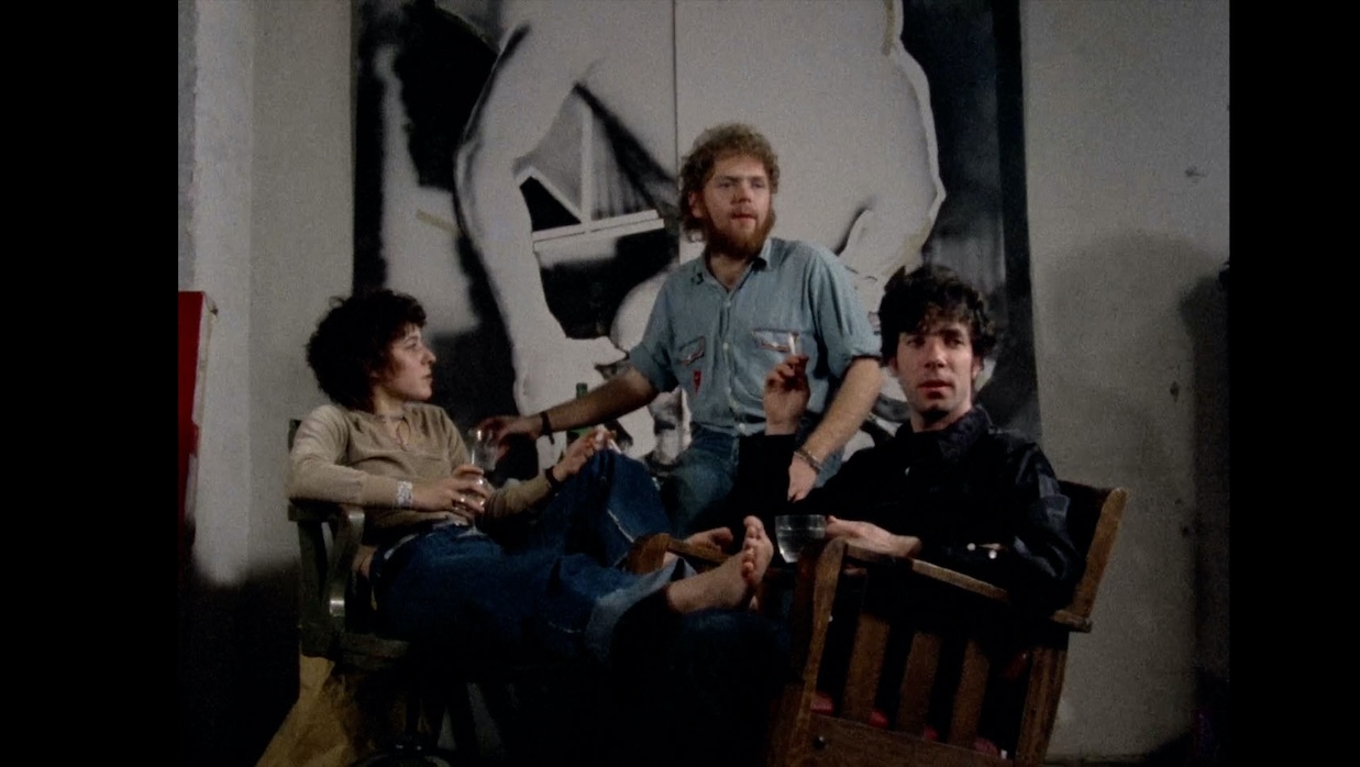 A woman and two men sit in front of a gigantic photograph.