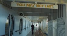 A man walks down the hallway of a long cruise ship.