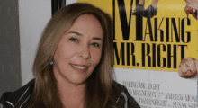 A white woman stands in front of a film poster.