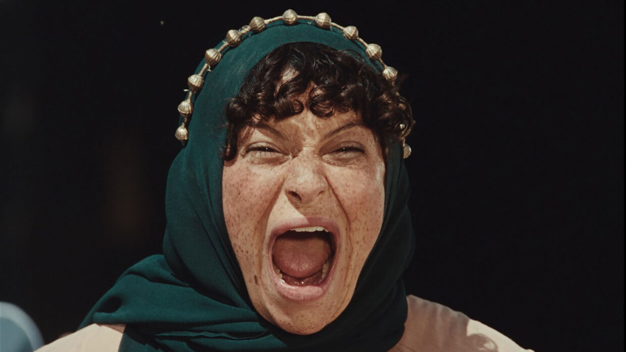 A woman with a green scarf around her head is screaming.