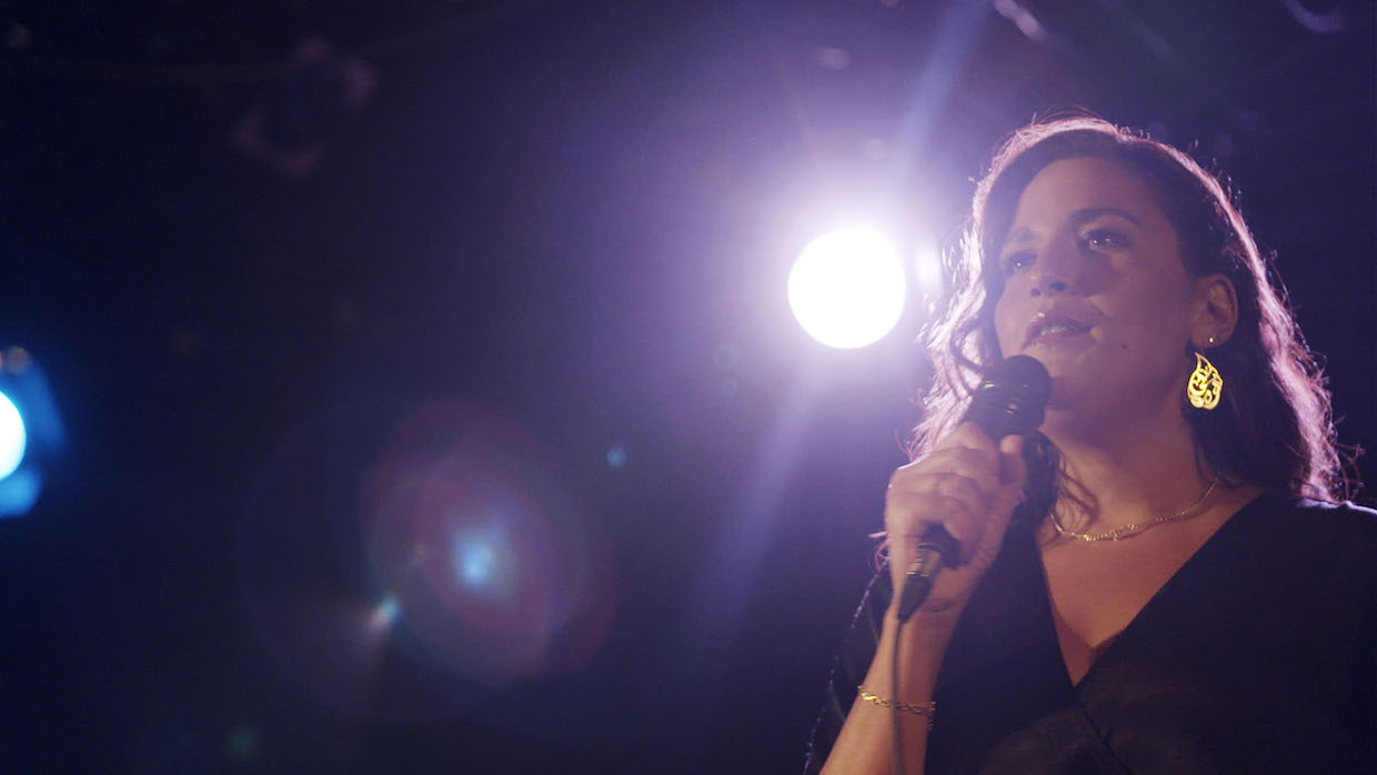 A woman stands on a stage holding a microphone.