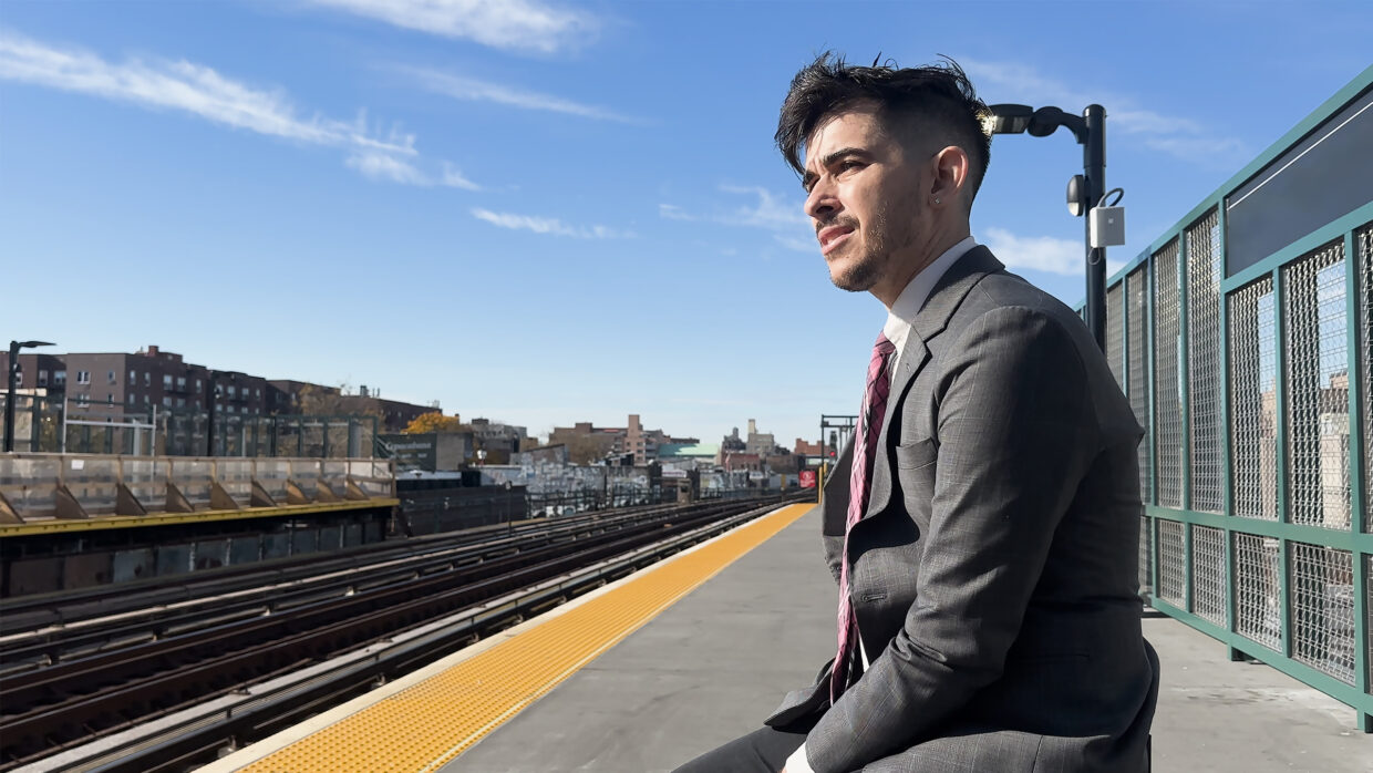 A young man in a suit is waiting at a train station.