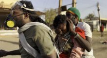 Three Sudanese wearing masks are in the streets.