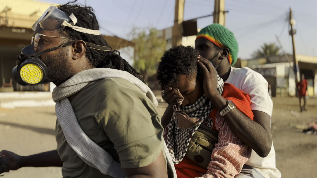Three Sudanese wearing masks are in the streets.