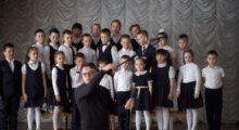 A group of uniformed schoolchildren and their teacher pose for a photo.