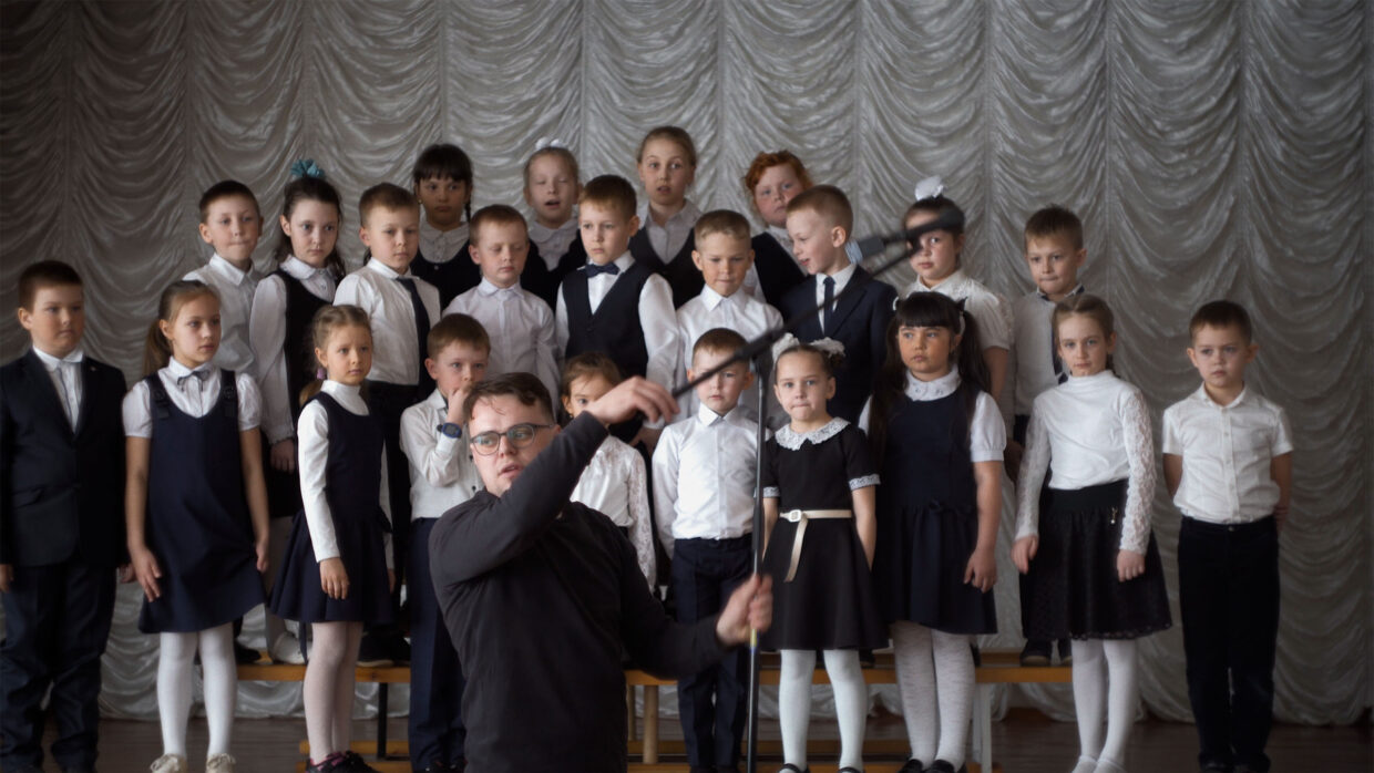 A group of uniformed schoolchildren and their teacher pose for a photo.