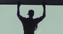 A black man with his arms raised is seen from behind