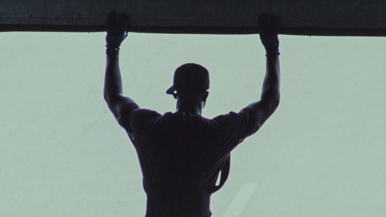 A black man with his arms raised is seen from behind
