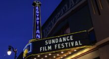 An illuminated movie theater marquee just before total sunset.