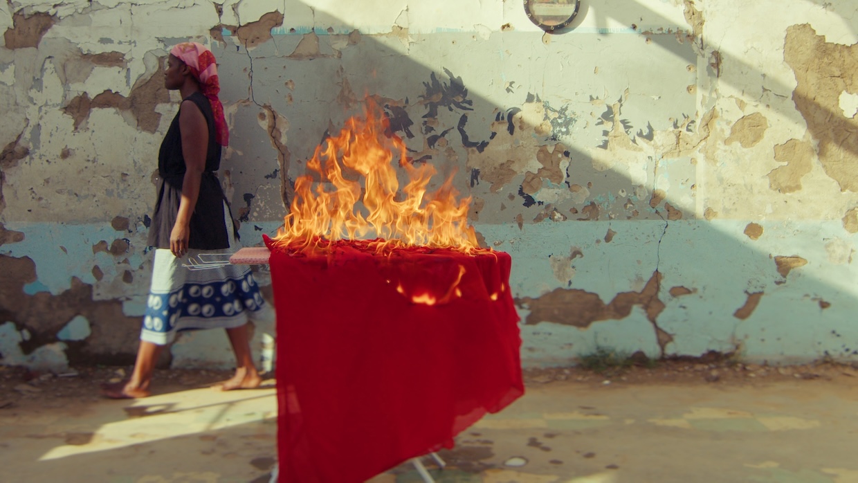 A woman walks past a table outside whose tablecloth is on fire.