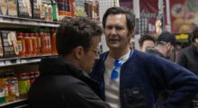 Two men talk to each other in a grocery store.