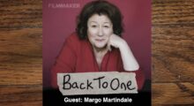 A middle-aged white woman with brown hair and a red top -- the actress Margo Martindale, leaning forward with her chin on her hand.