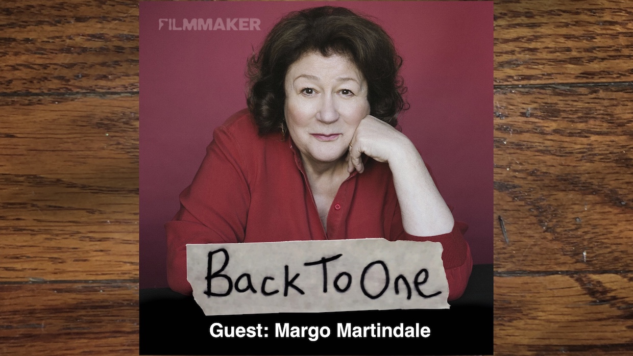 A middle-aged white woman with brown hair and a red top -- the actress Margo Martindale, leaning forward with her chin on her hand.