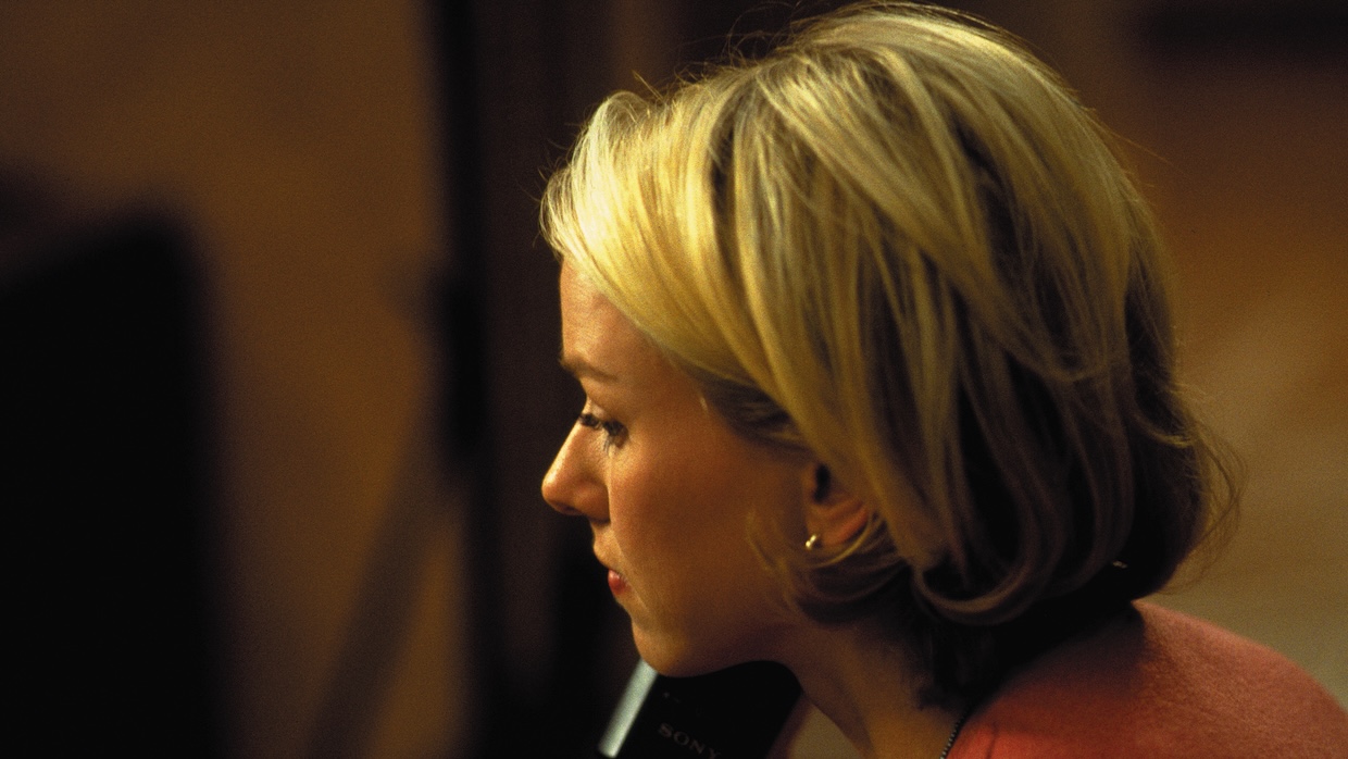 A blond woman holds a phone to her right ear.