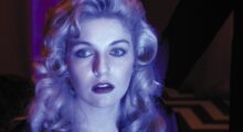A blond woman is illuminated in blue light.