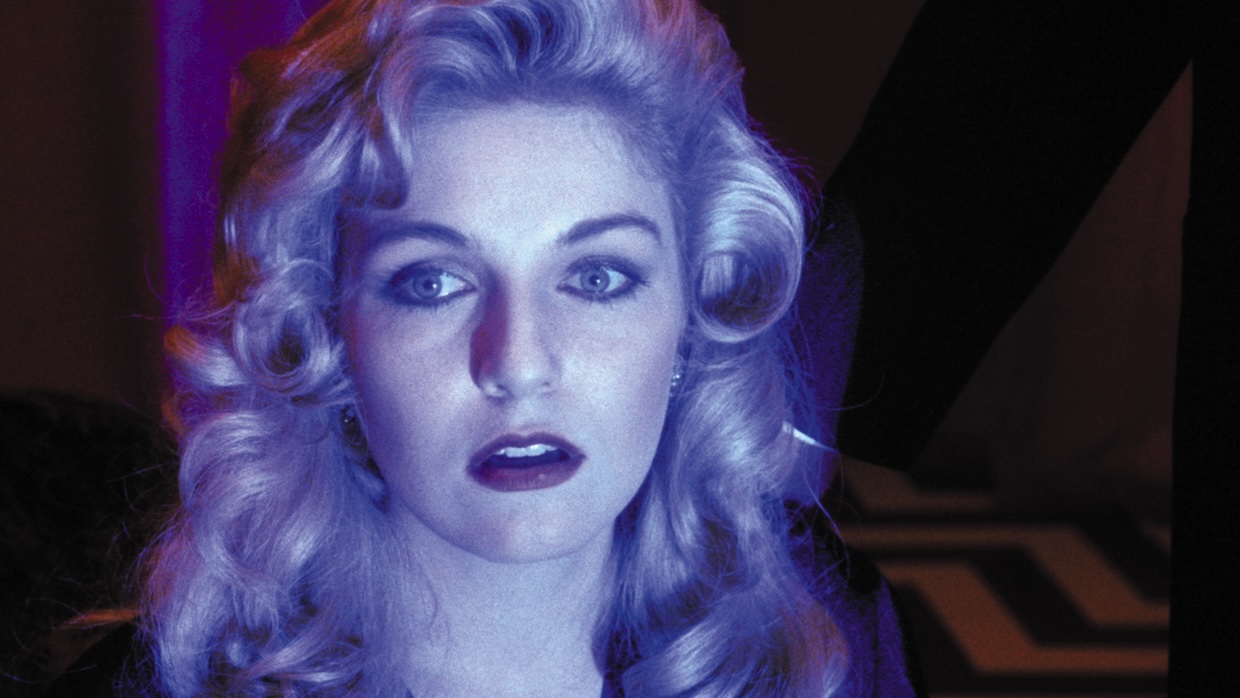 A blond woman is illuminated in blue light.